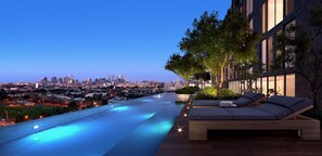 A rooftop infinity pool with a city view, a wooden deck, and a lounge area with cushions. - Quest Flemington Central (Flemington)