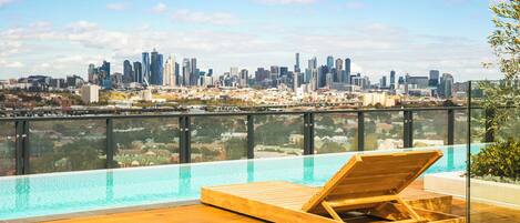 Een buitenzwembad, ligstoelen bij het zwembad