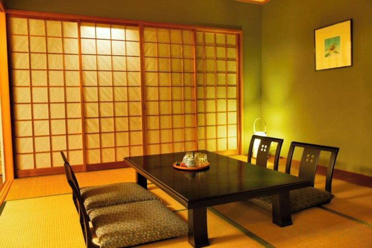 Une pièce de style japonais traditionnel, avec un sol recouvert de tatamis, une table basse et des portes coulissantes.