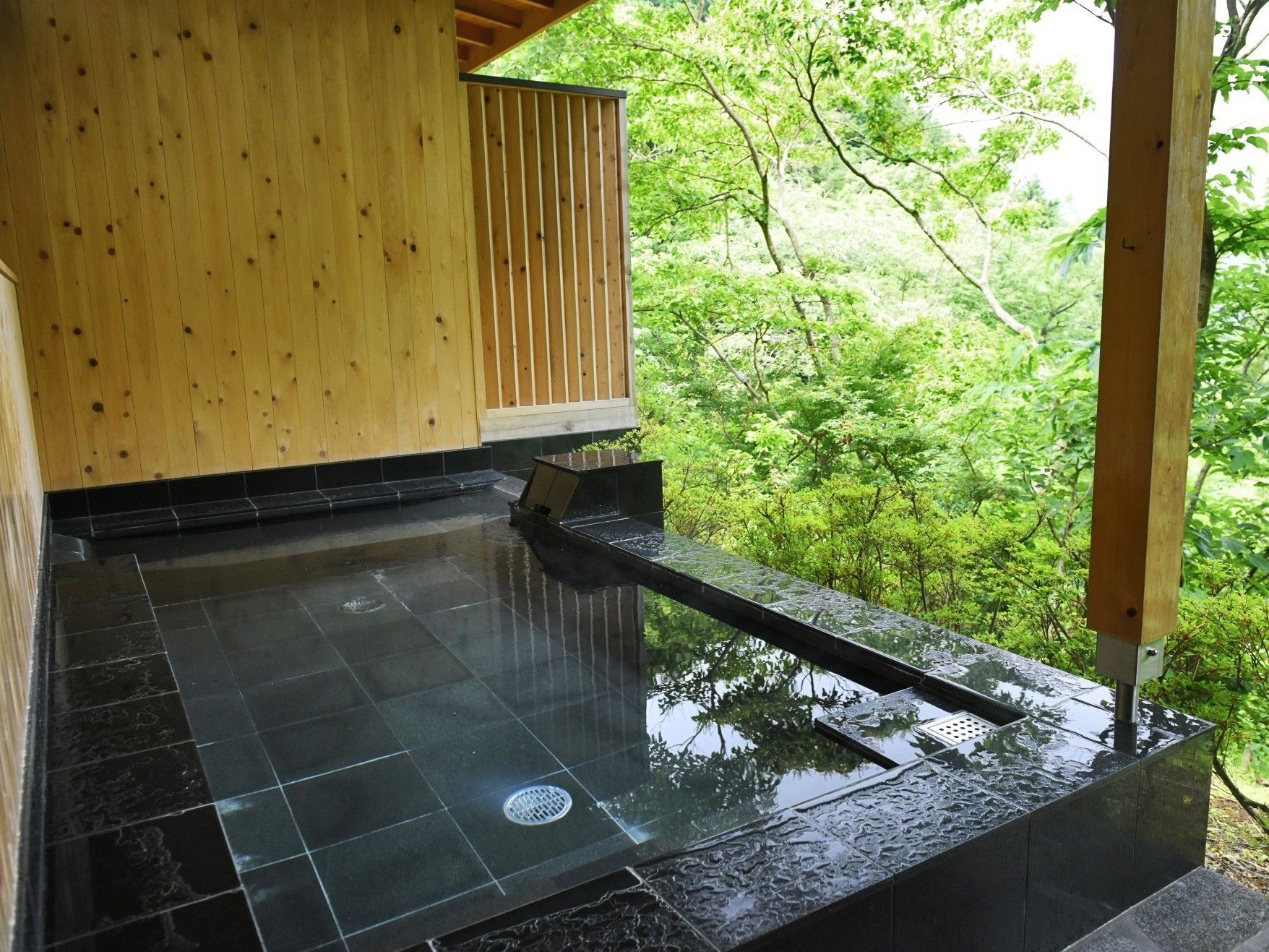 Uma casa de banho japonesa tradicional, com interior de madeira e vista para vegetação exuberante.