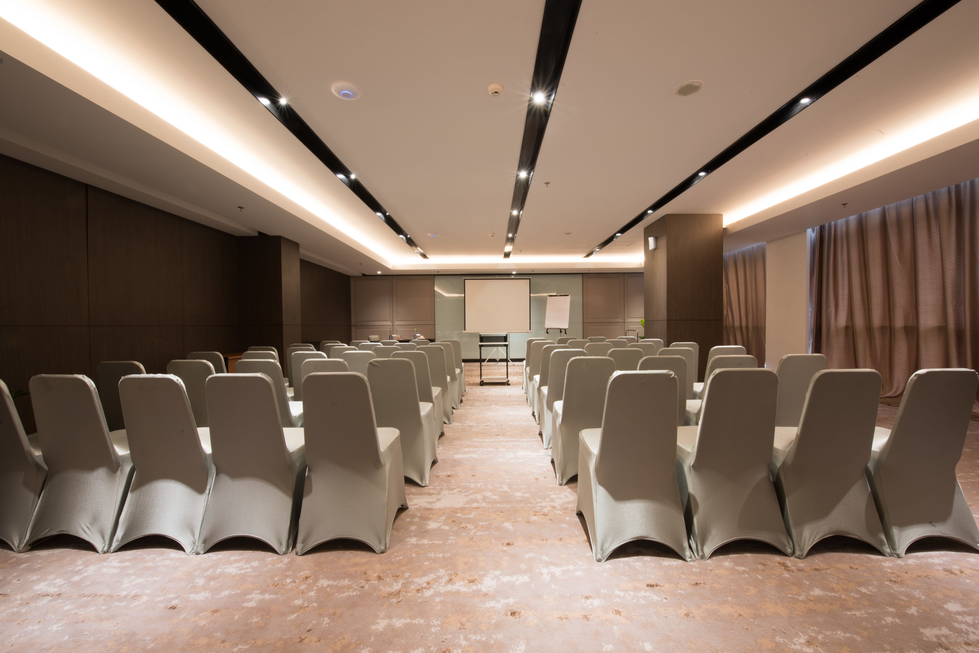 A conference room with rows of chairs, a podium, and a projector screen.