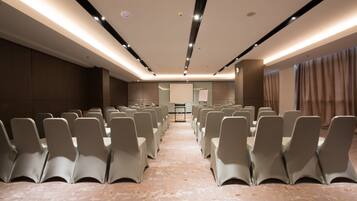 A conference room with rows of chairs, a podium, and a projector screen.