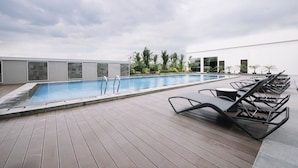 Zona de piscina en la azotea con sillones de descanso y vistas despejadas del cielo.