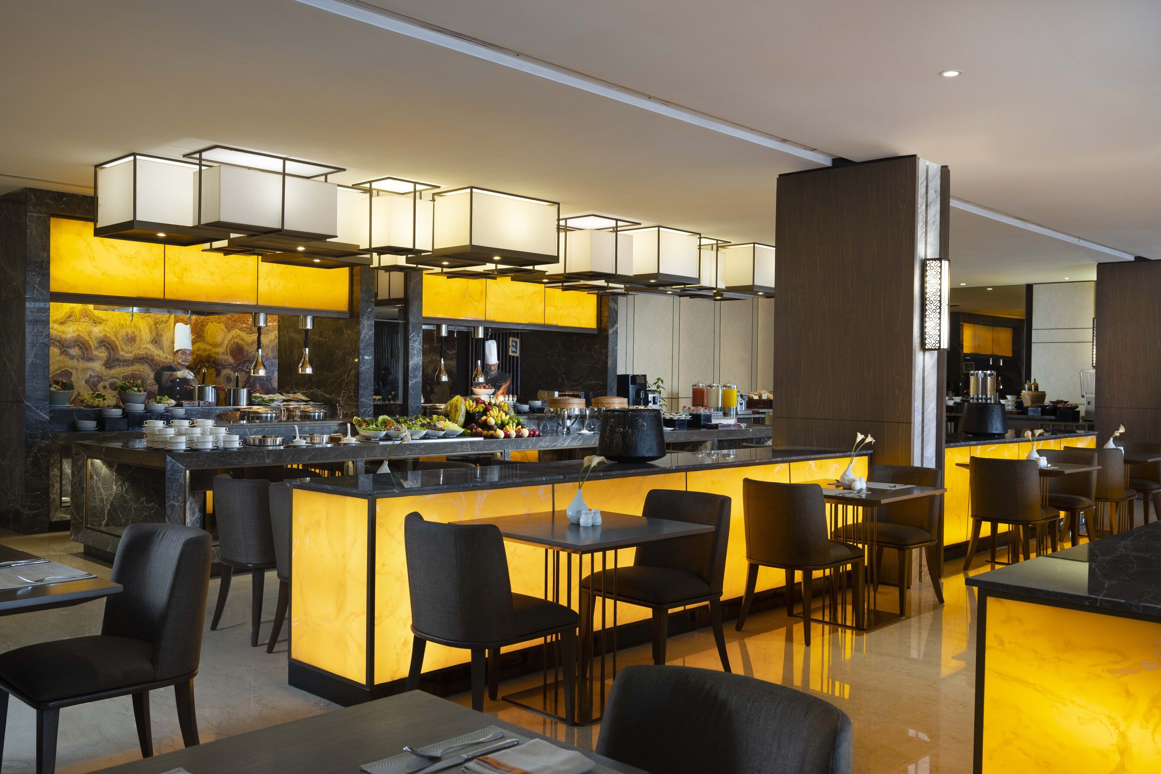Un restaurante moderno con una zona de bar, asientos y una cocina al fondo.