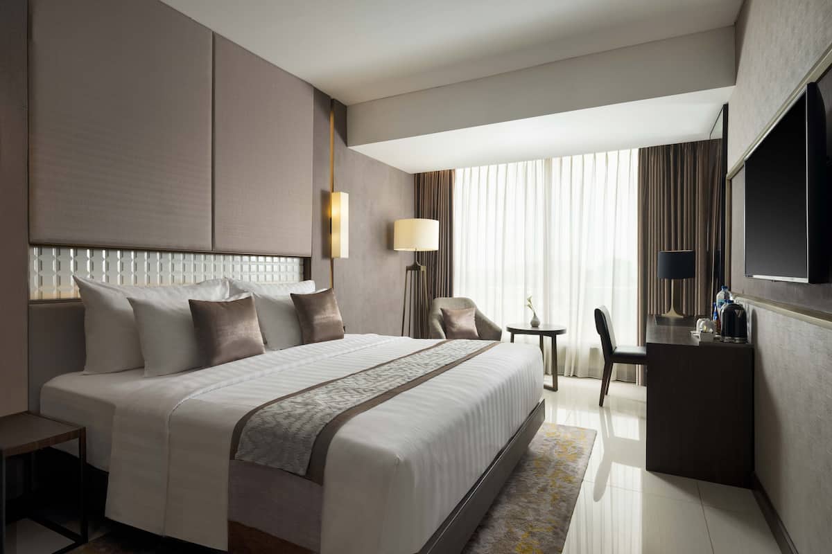 A modern hotel room with a large bed, a desk, and a television.