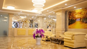 A hotel lobby with a reception desk, a large chandelier, a sofa, and a painting on the wall. - Pariat River Front Hotel (Da Nang)