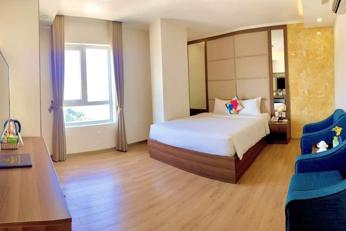 A hotel room with a bed, a desk, a TV, and a seating area.