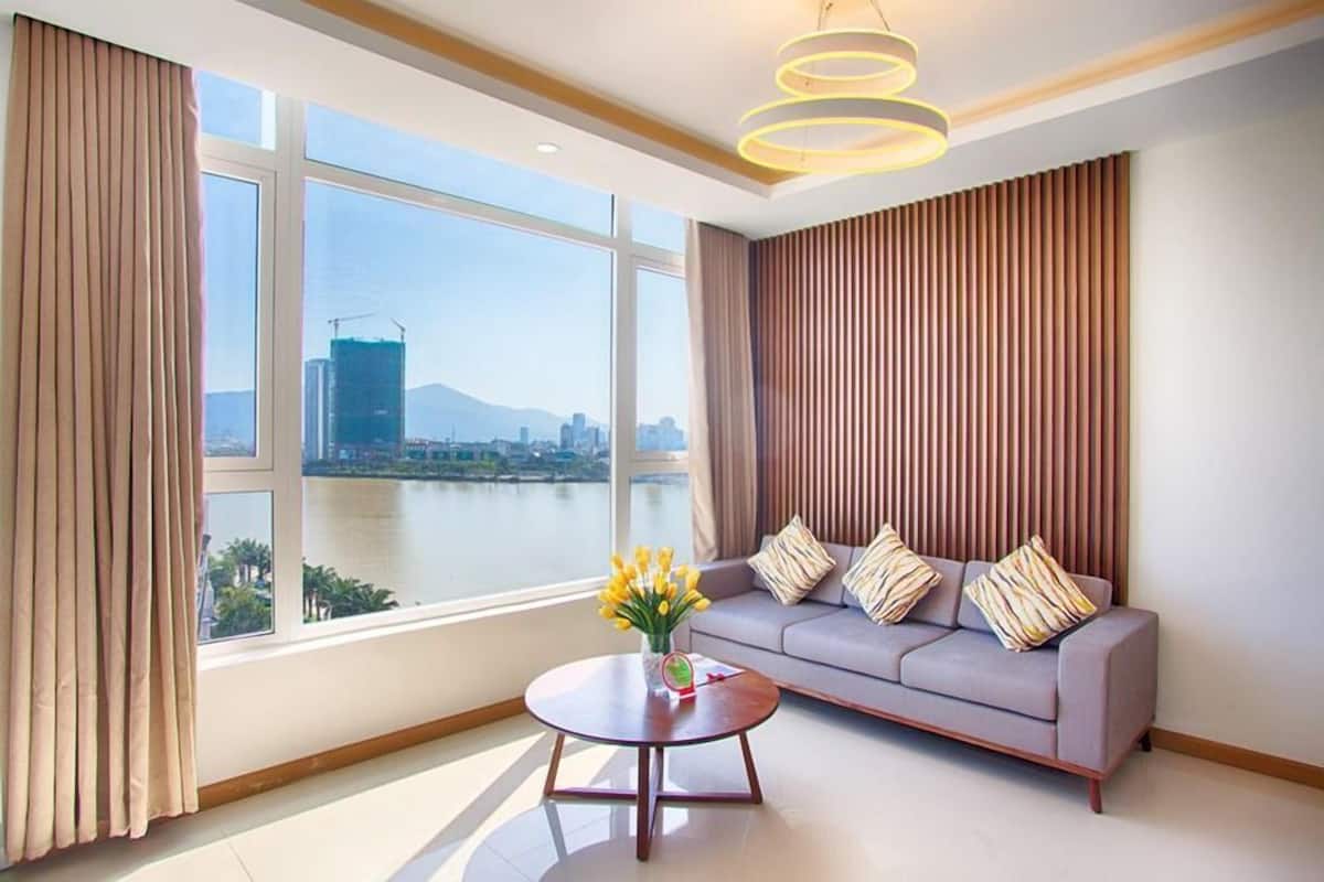 A modern living room with a large window, a sofa, a coffee table, and a decorative light fixture.