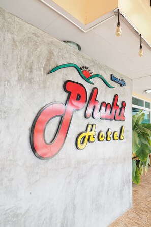 Experience the Phakhi Hotel's coastal charm with its iconic sign featuring a stylized wave and bird logo.