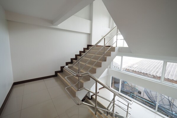 A modern staircase with glass railings, leading to a second floor with large windows.