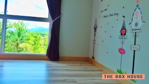 A room with large windows, a wooden floor, and a wall decorated with love-themed illustrations and text. - The Box House (Krabi)