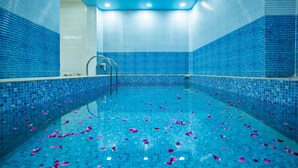 A swimming pool with blue tiled walls and floor, and rose petals scattered on the water. - Hotel Marina Mahal (Jaisalmer)