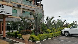 A hotel reception area with a modern building facade, a parking lot, and well-maintained landscaping. - Golden Zambezi Lodge (Lusaka)