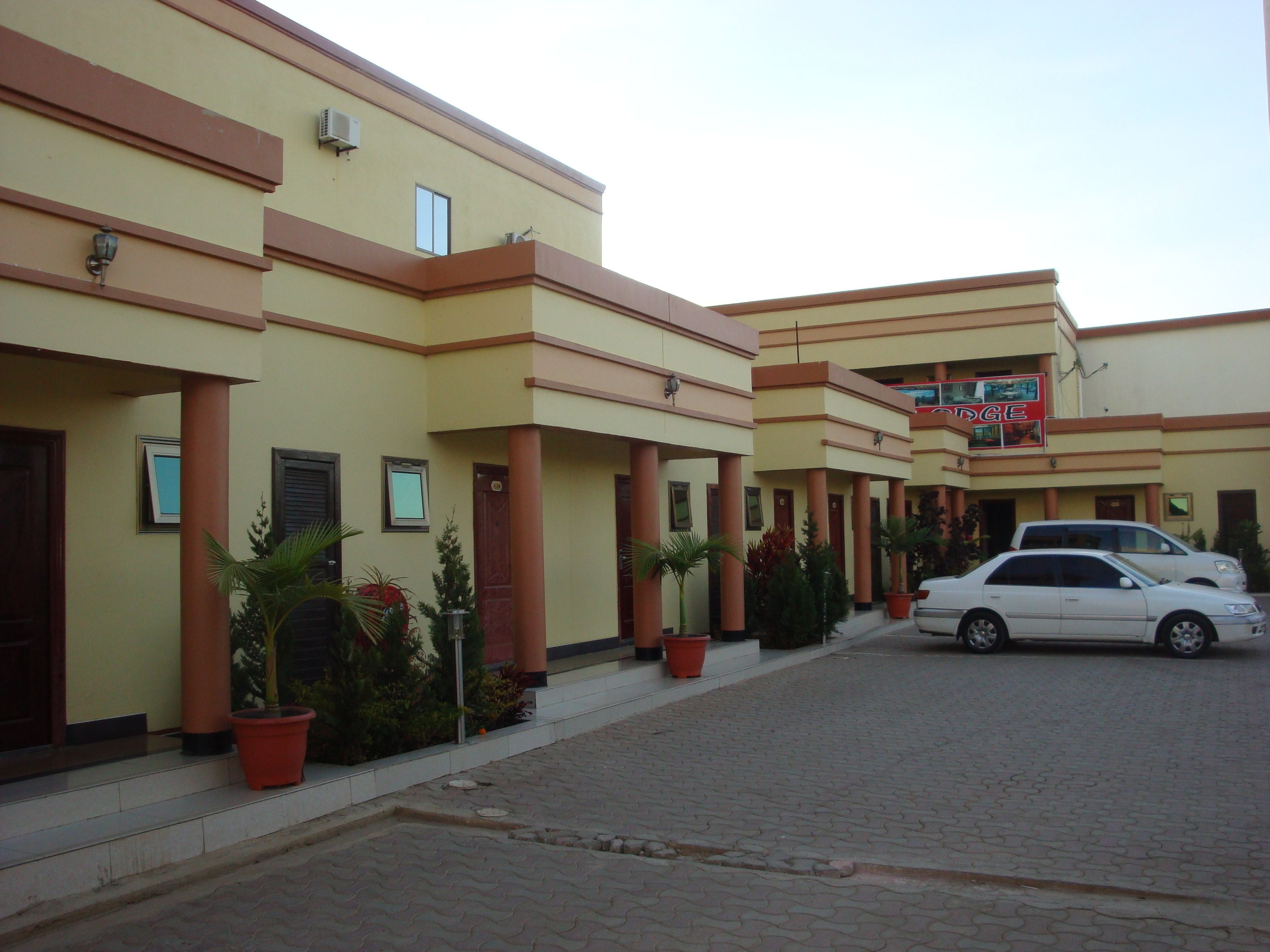 A hotel with multiple floors, a central entrance, and a parking area with cars.
