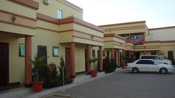A hotel with multiple floors, a central entrance, and a parking area with cars.