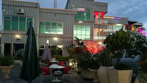 A modern building with a bar area, outdoor seating, and potted plants. - Golden Zambezi Lodge (Lusaka)