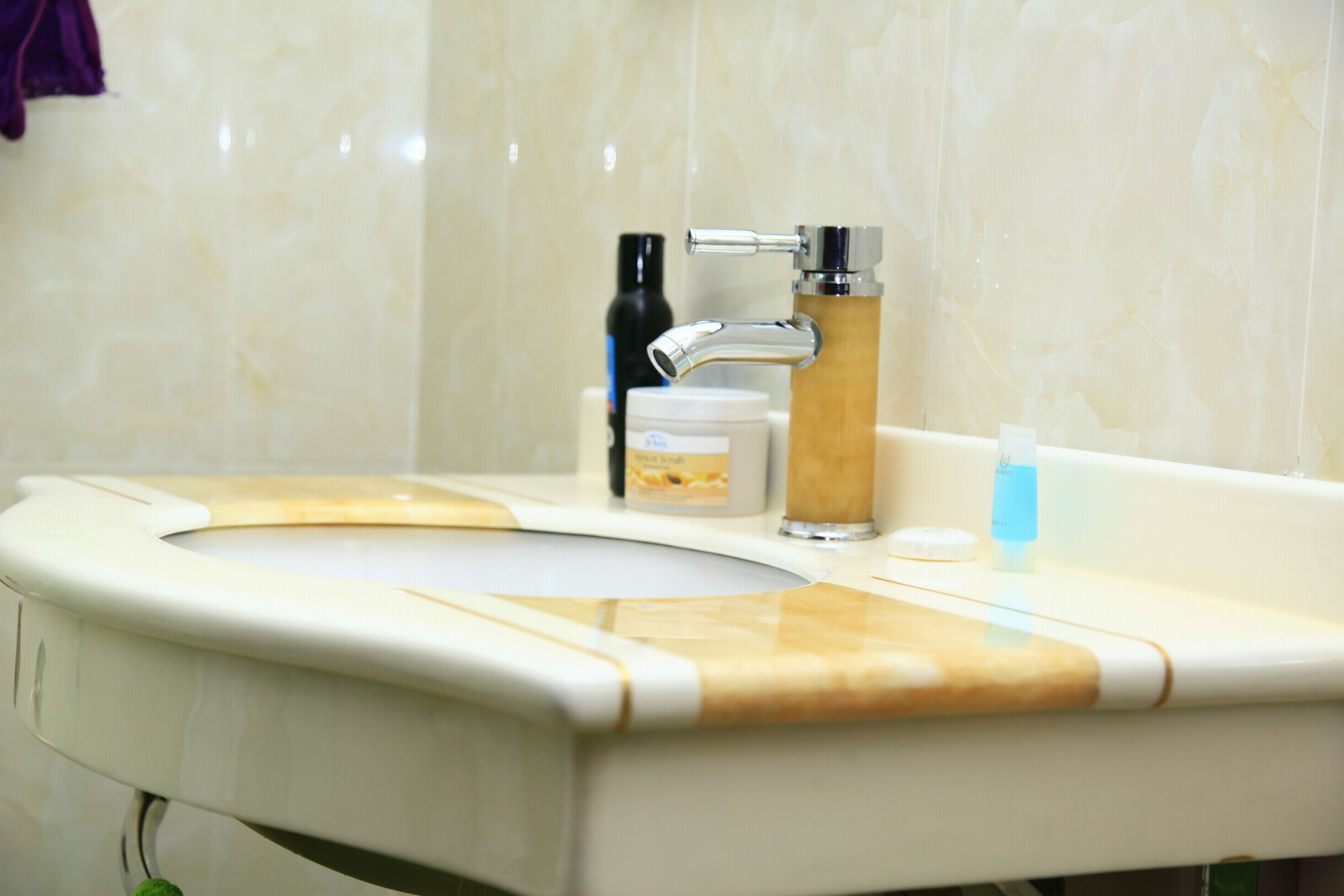 A bathroom with a sink, a faucet, and toiletries on the counter.