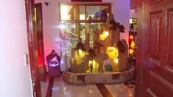 A hotel lobby with a decorative fountain, a vase with flowers, and a large window.