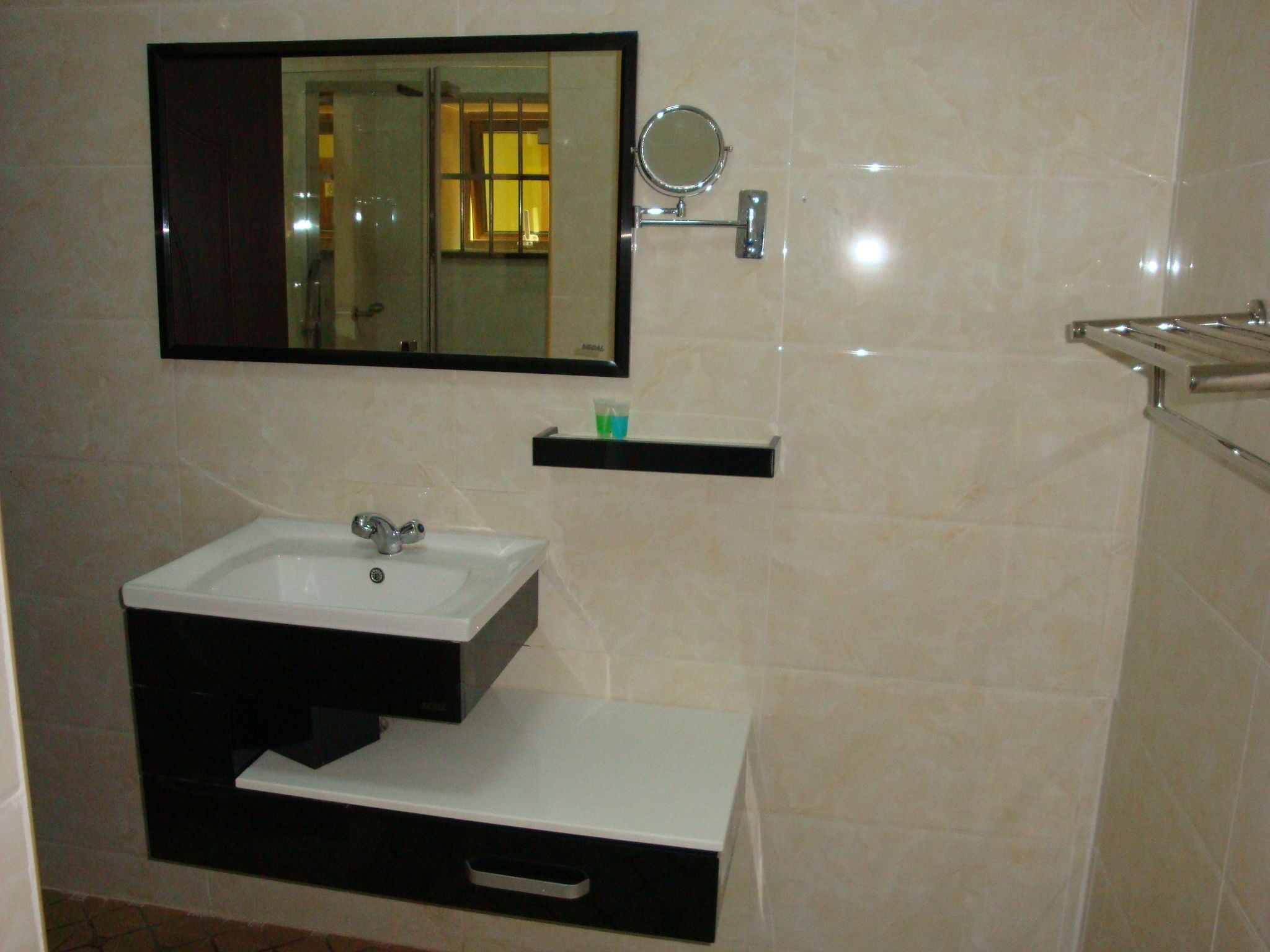 A bathroom with a white sink, a mirror, and a towel rack.