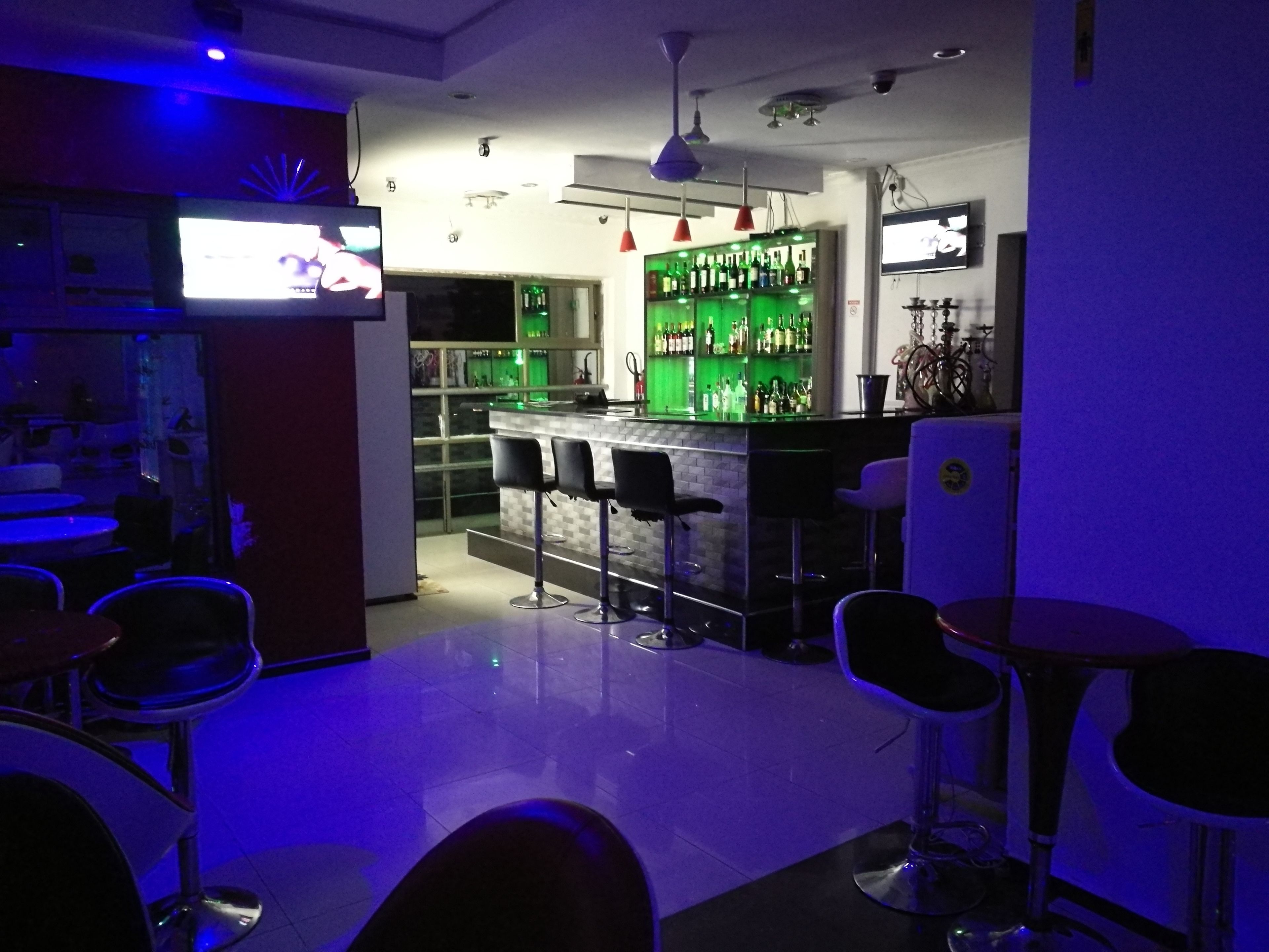 A bar area with a counter, stools, and a bar stocked with bottles.