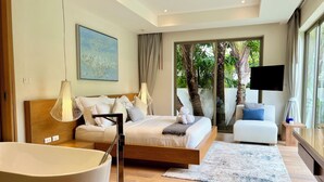 A modern bedroom with a large bed, a sitting area, and a bathtub. - Trichada Villas by RESAVA (Choeng Thale)