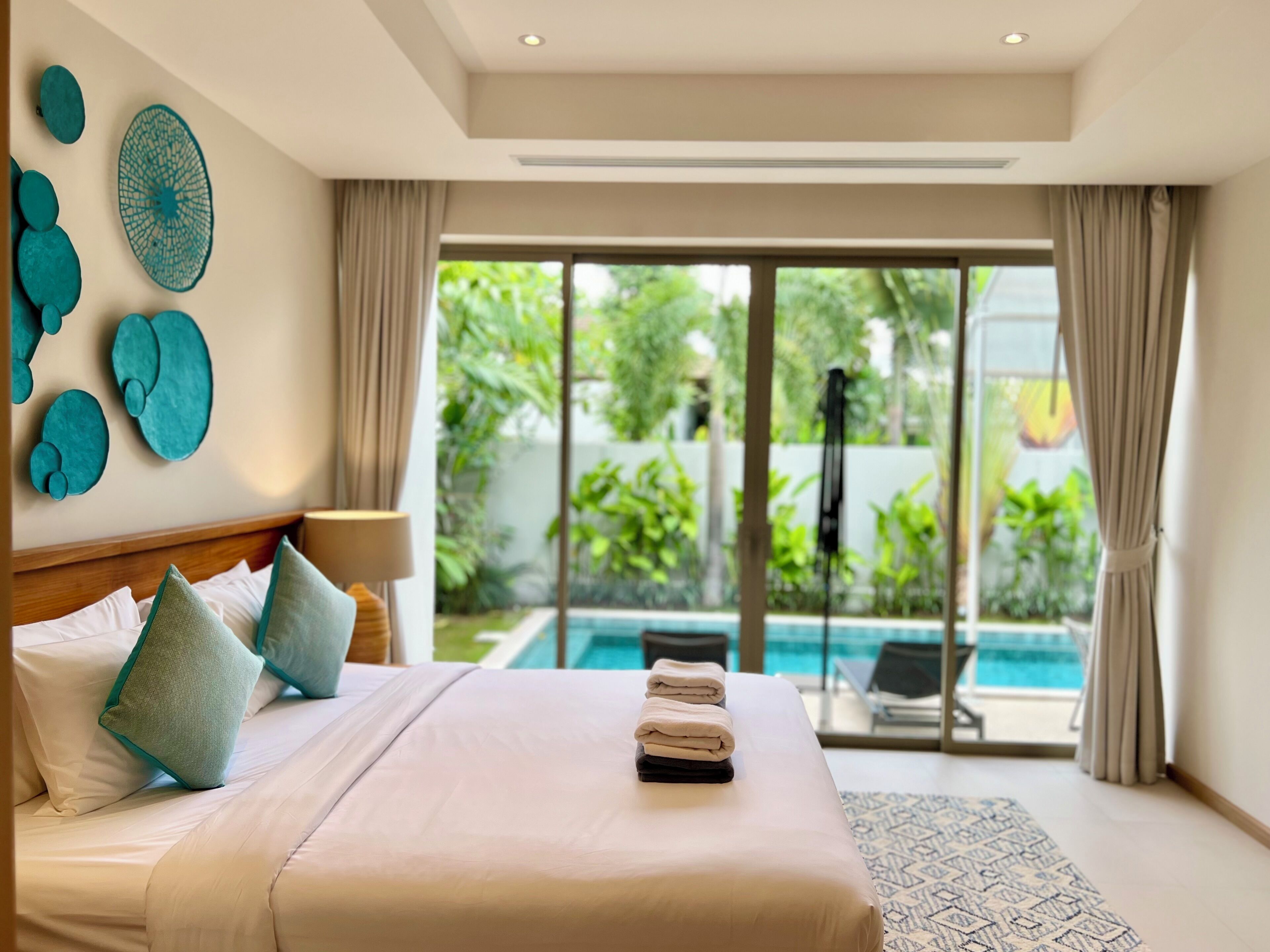 Une chambre d’hôtel avec un grand lit, une vue sur une piscine et un jardin tropical.
