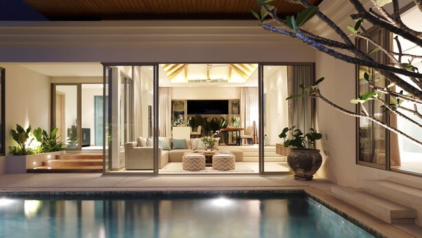 A modern indoor pool area with a seating area, glass doors leading to a living room, and a large potted plant. - Trichada Villas by RESAVA (Choeng Thale)