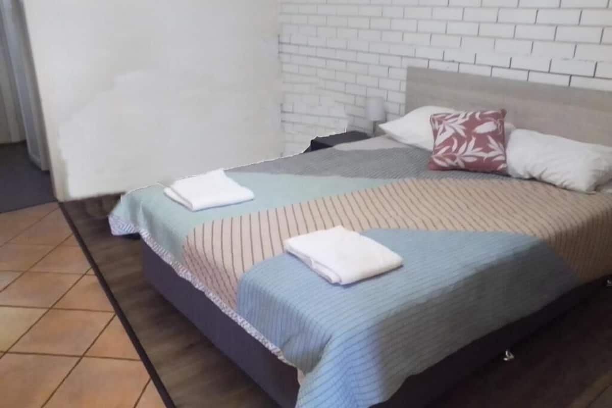 Uma cama com um edredom listrado, um travesseiro com padrão floral e um travesseiro branco.