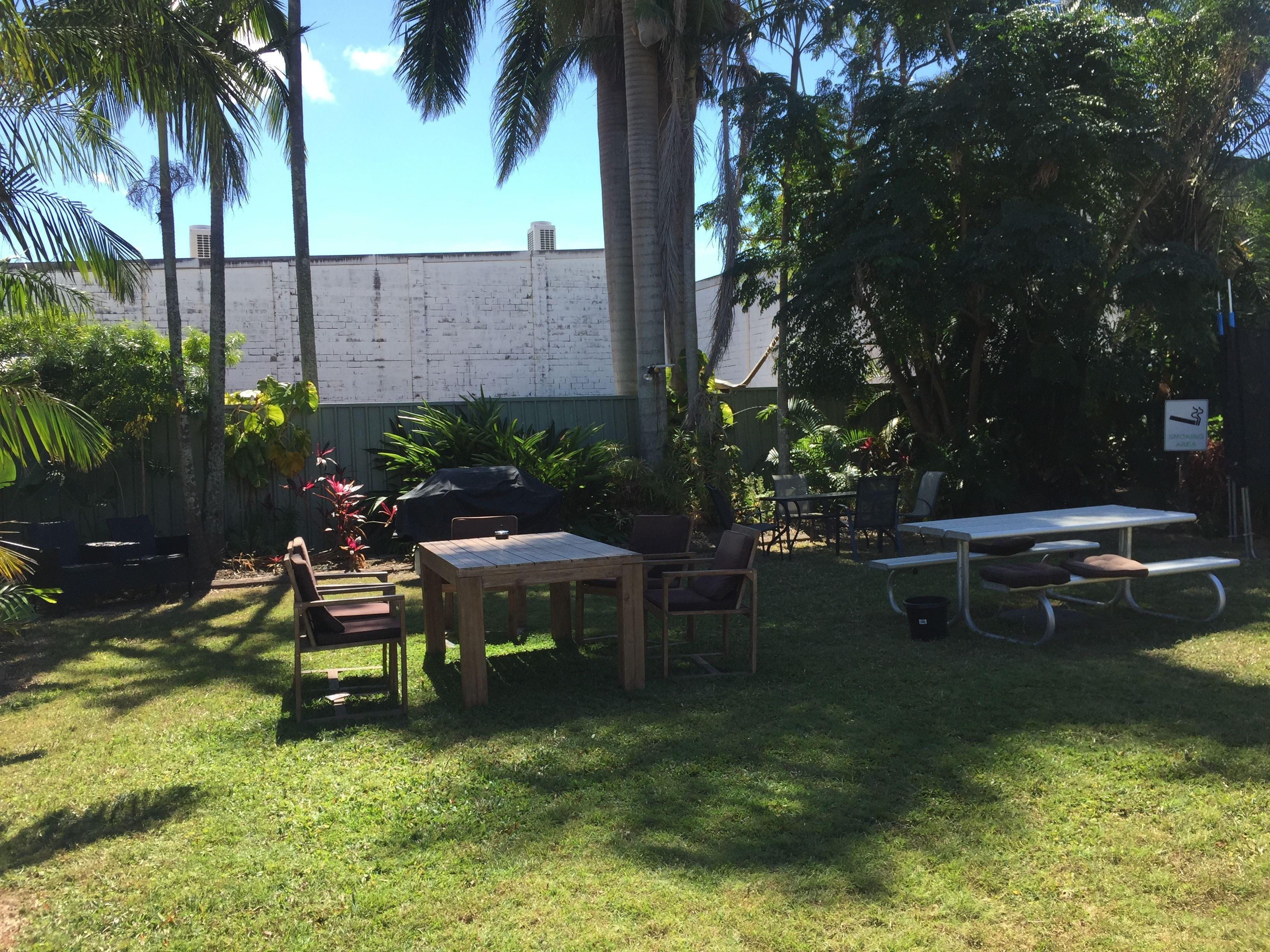 An outdoor patio area with a table and chairs, surrounded by lush greenery and palm trees.