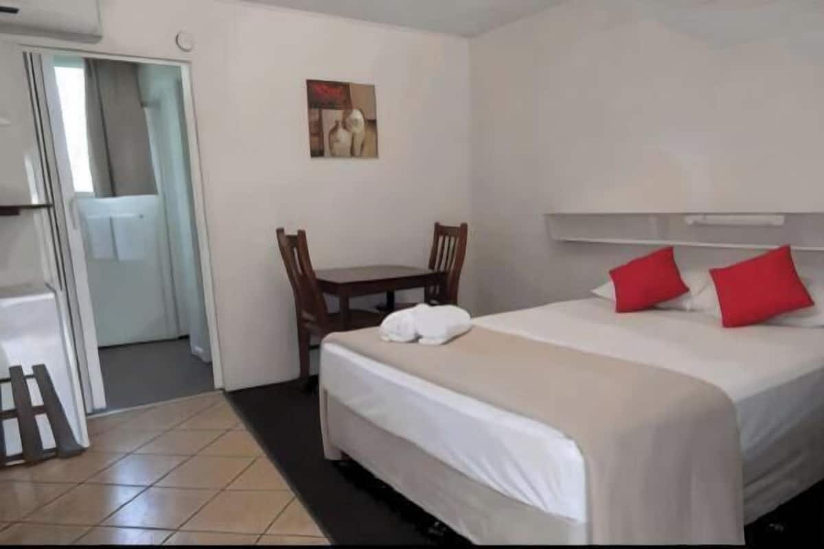 Quarto de hotel com cama, cadeira, mesa e um quadro na parede.