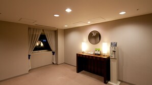Habitación de hotel con escritorio, teléfono, lámpara y panel de control en la pared.