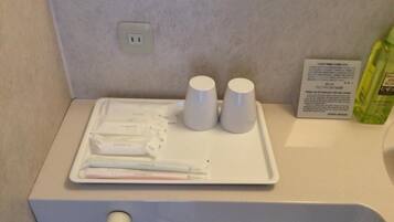 A hotel bathroom with a tray of toiletries, two white cups, and a bottle of soap.