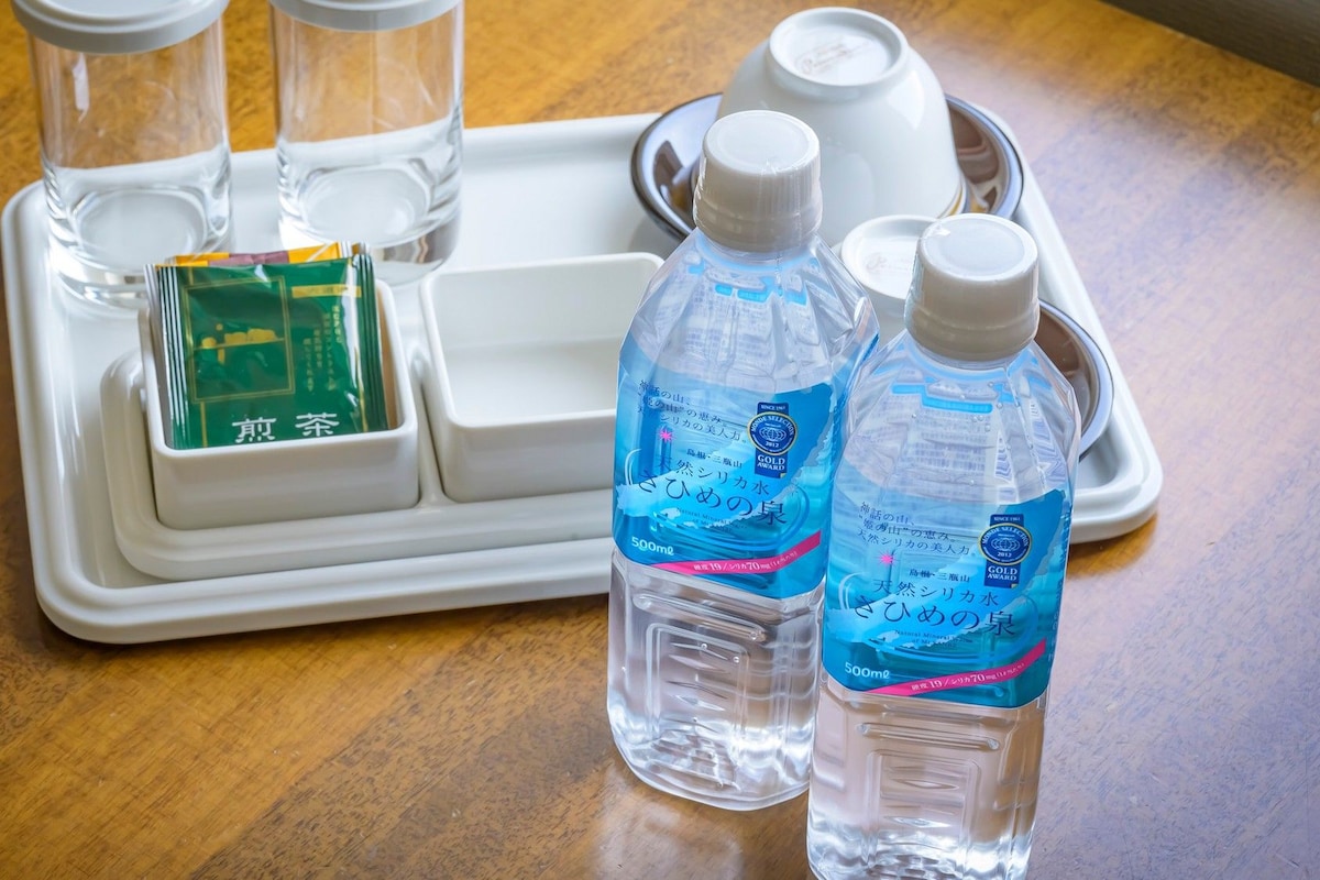 A tray with two bottles of water, a green tea packet, and a white container.