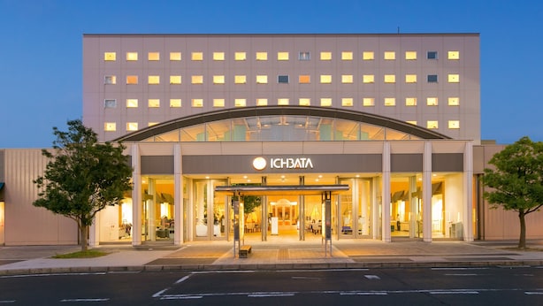 Un hotel moderno con entrada de cristal, un letrero llamativo y techo plano.
