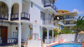 Ein Hotel mit Schwimmbad, mehreren Balkonen und blauem Himmel.