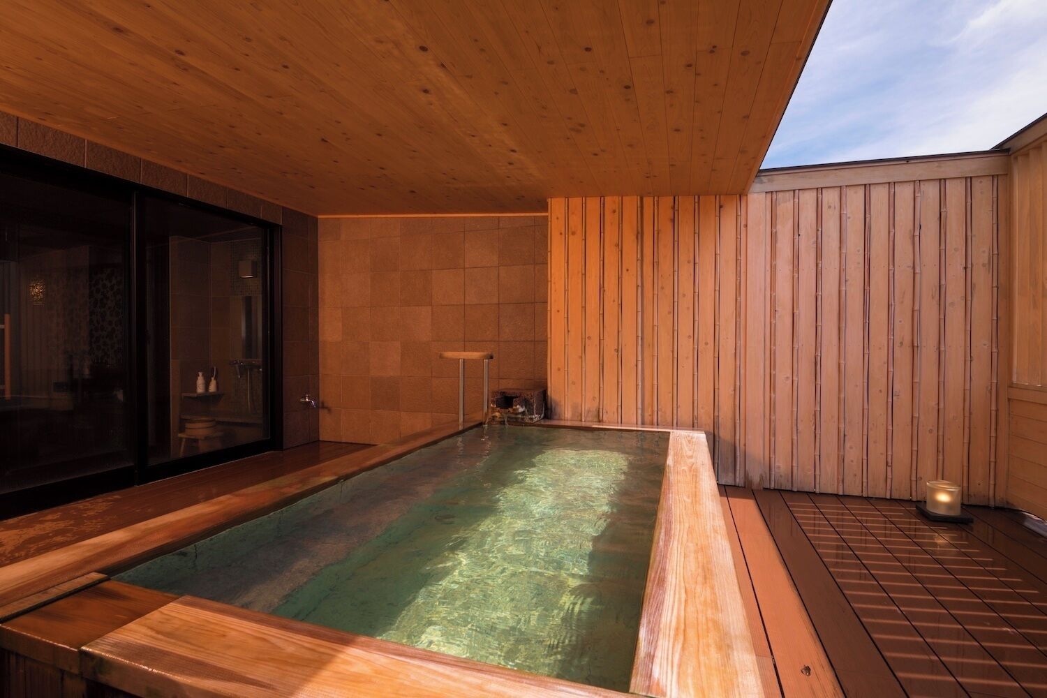 A hot tub area with wooden flooring and walls, a glass enclosure, and a wooden ceiling.