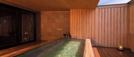 A hot tub area with wooden flooring and walls, a glass enclosure, and a wooden ceiling.