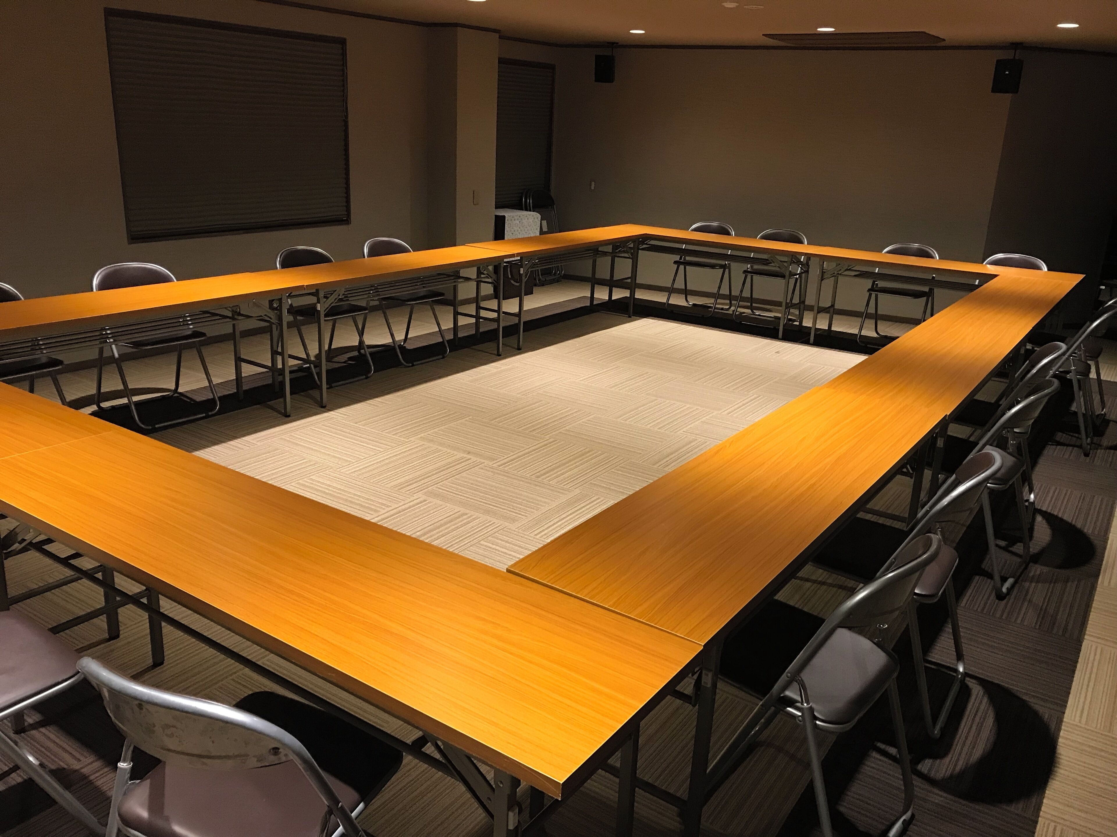 Un salón de conferencias con una larga mesa, sillas y piso alfombrado.