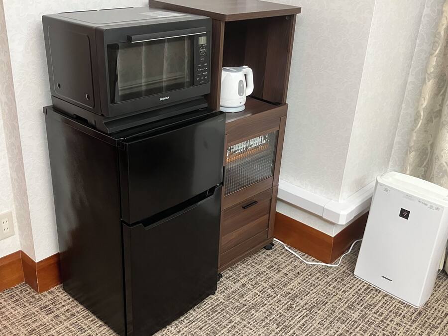 A compact kitchenette with a black refrigerator, a microwave, a small coffee maker, and a mini fridge.