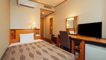 A hotel room with a bed, desk, chair, television, and a refrigerator.