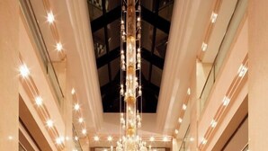 A grand lobby with a grand piano, a chandelier, and a red curtain backdrop. - Hotel Racine Sinmaebashi (Maebashi)