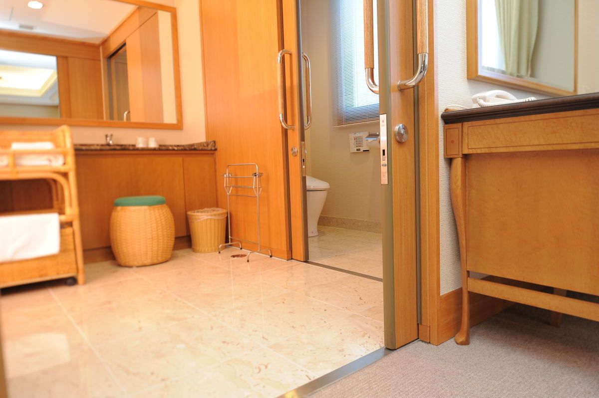 A compact bathroom with a toilet, a sink, and a mirror. There is a small trash bin and a wicker basket.