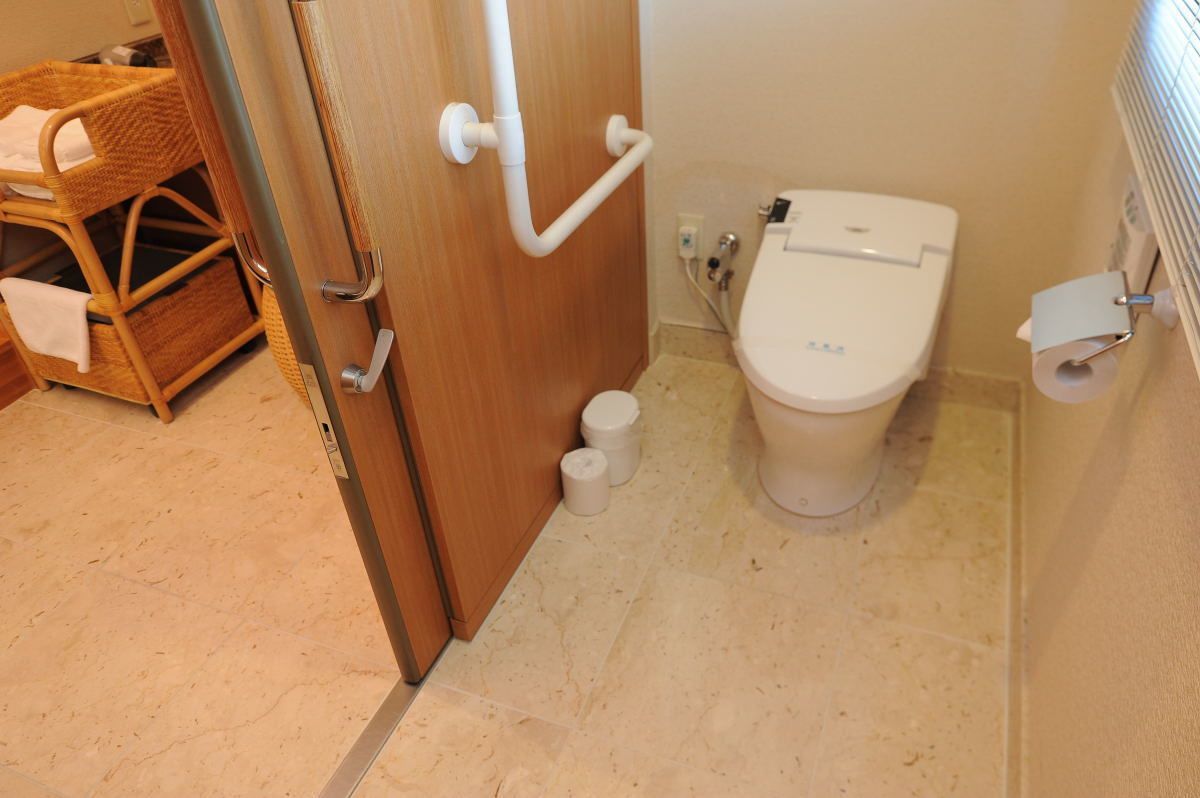 A bathroom with a toilet, a bidet, and a handrail.