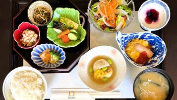 Variedad de platos japoneses dispuestos en una bandeja, incluyendo arroz, sopa y diferentes tipos de sashimi y ensalada.