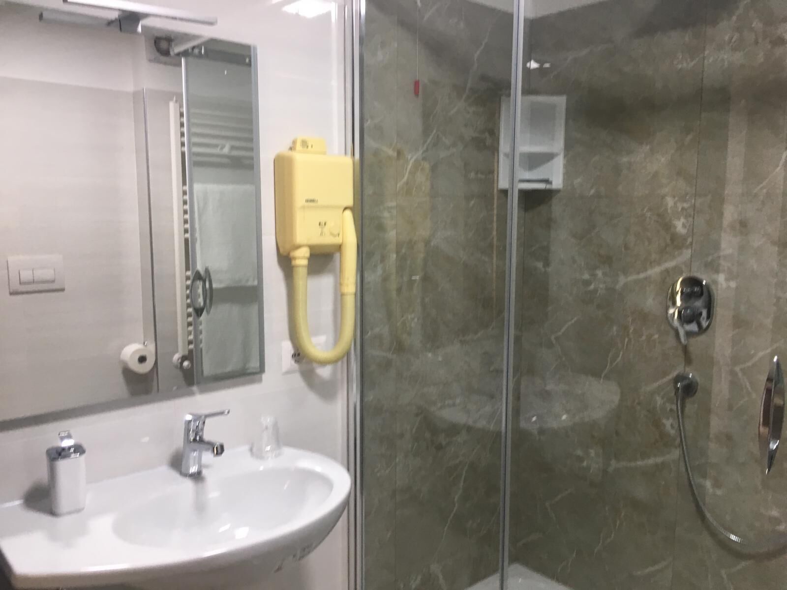 A bathroom with a white sink, mirror, and a glass shower enclosure.