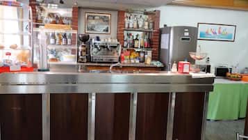 A bar area with a coffee machine, shelves with bottles, and a refrigerator.