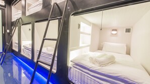 A train compartment with bunk beds, a ladder, and a window.