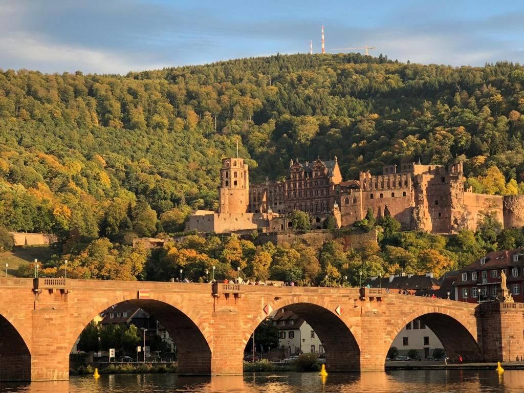 A historic bridge with multiple arches spanning a river, leading to a castle on a hill.
