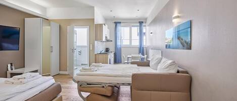 Ein modernes Hotelzimmer mit Bett, Sofa, Fernseher und Schreibtisch.