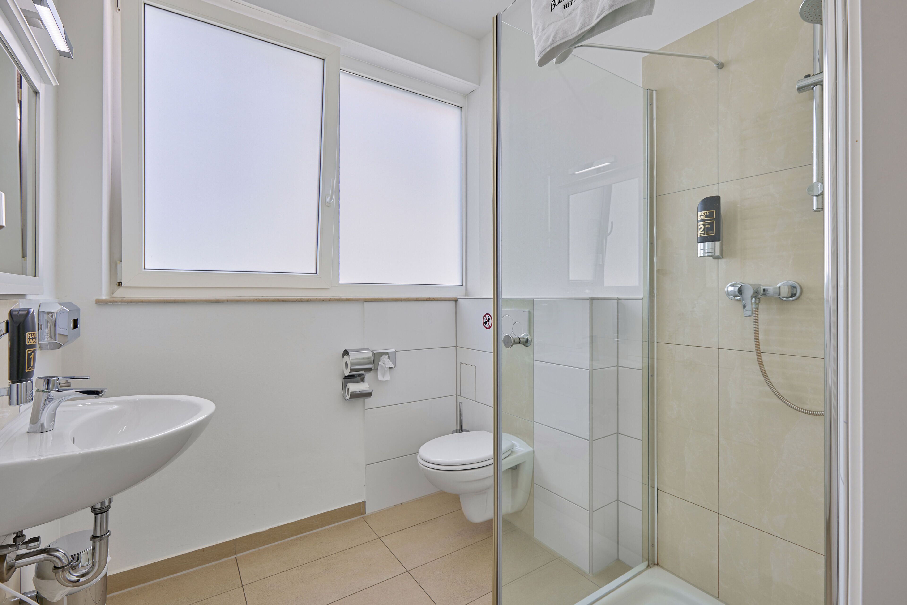 A modern bathroom with a sink, toilet, and glass-enclosed shower.